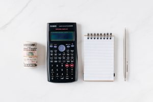 dollar bills next to a calculator to calculate how to make money quickly